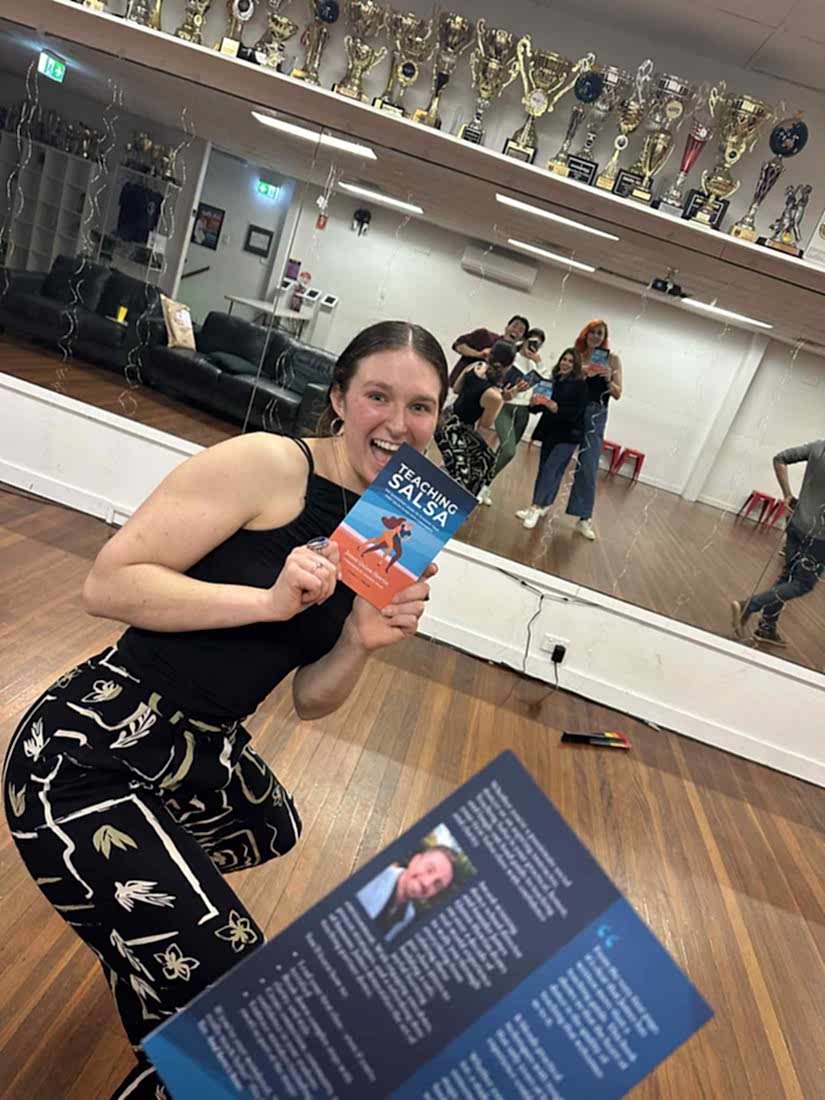 A delighted Dance Culture student holding a copy of Teaching Salsa in the studio