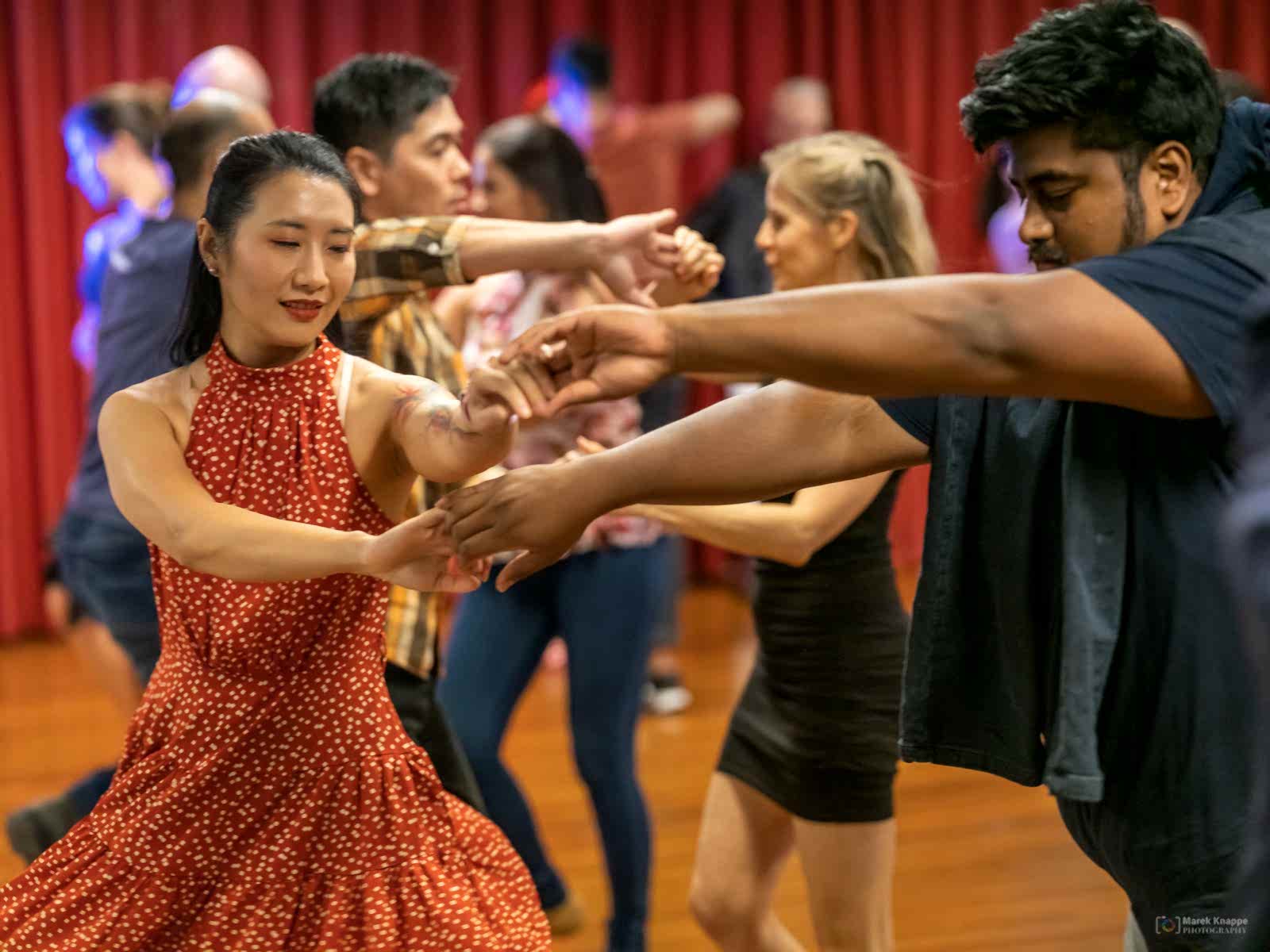 A pair mid-spin dancing Salsa in a red dress